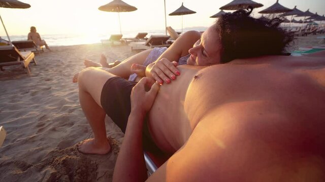 Couple on honeymoon vacation lying on beach ejoyng romantic view of sunsetnear the blue ocea