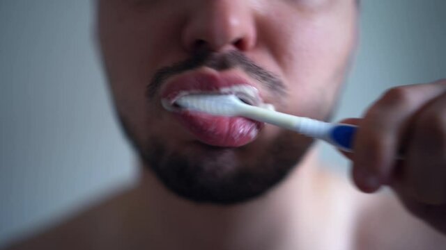 Man brushing teeth with toothbrush and toothpaste. Smiling handsome guy enjoying morning oral anticavity hygienic routine alone in bathroom. Brush your teeth. 