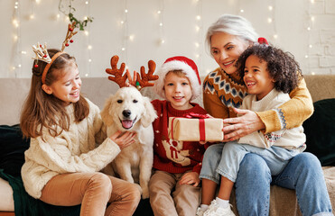 Happy multiethnic family, grandmother with grandchildren and dog enjoying Christmas day