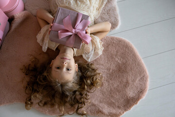 Top view of a lying girl in a beautiful dress.The girl has a gift in her hands