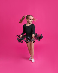 Cute little girl in black dress dancing on pink background
