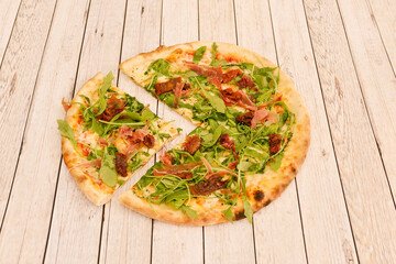 Small pizza with serrano ham with arugula and dehydrated tomato