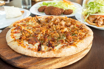 Freshly made pizza with ingredients and kebab meat or shawarma with cheese and cooked in a stone...