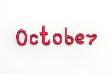 The word October is made of red plasticine on a white background