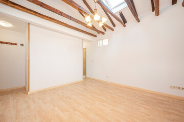 Living room empty of furniture with exposed wooden beams, air conditioning unit and wooden flooring