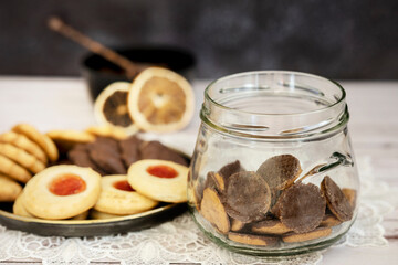 Glass jar with chocolate cookies and tea cookies on a vintage metal plate and dried citrus slices