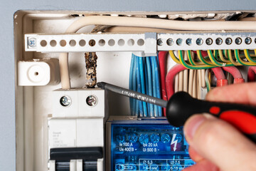 Man points screwdriver at damaged electrical wire.