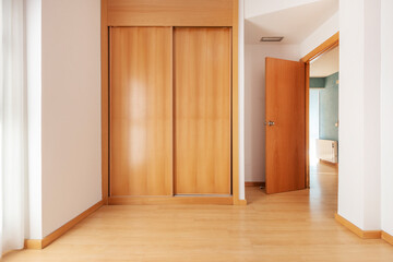 Obraz premium empty bedroom with built-in cherry wood wardrobe and light wooden floors