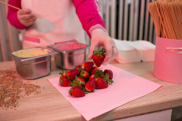 The pastry chef girl chooses strawberries for her cooking. chocolate-covered strawberries. Dipping in chocolate icing.