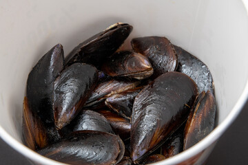 Fresh stuffed mussels in bucket on dark stone background