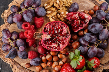 Ripe fresh fruits, berries and nuts served on a wooden tray