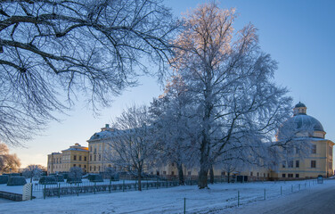 Sunny winter view over the Drottningholm palace a pale winter day, frosty trees and snow layer on roofs and ground, in Stockholm