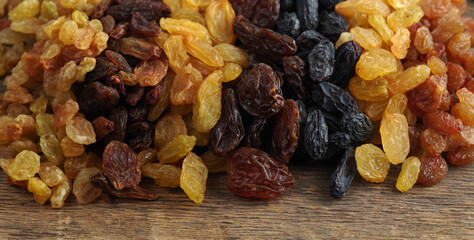 Various varieties of raisins on a woody texture background. Selective focus.