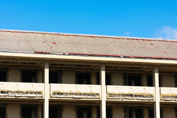 Side view of a pitched roof with removed clay roof tiles during office building demolition project. Several broken roof tiles left on rooftop underlayment