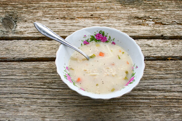 Home made chicken soup with noodles ,parsley and vegetables in white bowl . Healty soup