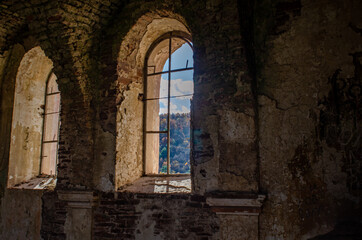 Fototapeta na wymiar View of forest under blue sky through windows of old ruined church.