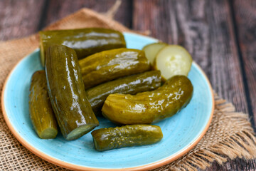  Plate of  homemade  organic bio pickled cucumbers  in vinegar with dill ,garlic and mustard seeds against dark rustic background
