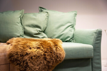Light green sofa with pillows, plaid and fur cape, Living room furniture