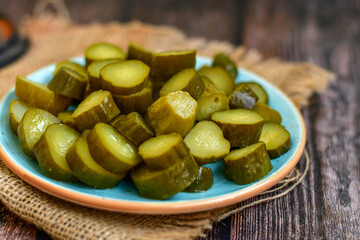  Plate of  homemade  organic bio pickled cucumbers  in vinegar with dill ,garlic and mustard seeds against dark rustic background
