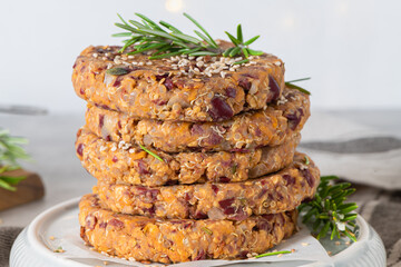 Raw veggie burger with quinoa, red beens, vegetables and rosemary leaves on kitchen countertop