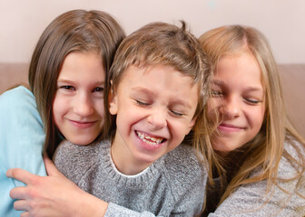Two girls hug their brother. The boy laughs . Happy children portrait close-up