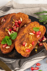 Traditional Christmas Rabanadas with lemon zest, pomegranate, pine nuts and cinnamon. Spanish Torrijas or french toasts close up on the countertop