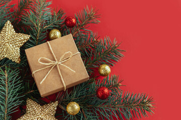 Gift box with spruce branches and christmas ornaments  on a red background. Holiday concept.