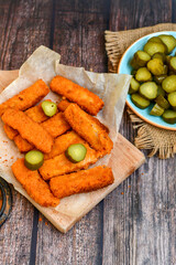 Close up of   Crispy breaded  deep fried fish fingers with breadcrumbs served  with remoulade sauce and  lemon Cod Fish Nuggets on rustic wood table background