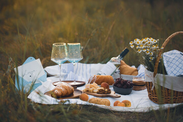 A picnic on the grass with wine and croissants. breakfast with a croissant. French breakfast. Food on the street. Croissants in nature. Romantic breakfast. Beautiful breakfast with champagne 