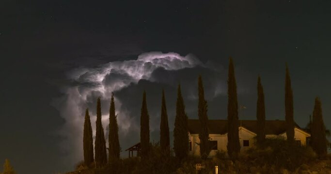Timelapse video of the lightning storm behind a mansion house on top of a mountain surrounded by tall trees
