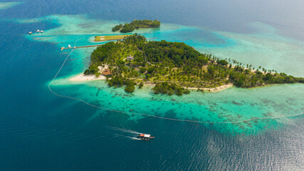 Malipano island with a sandy beach and azure water surrounded by a coral reef and an atoll, aerial view. Philippines, Samal.