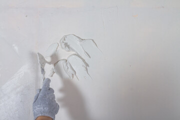 Apply plaster white putty on a concrete wall with a spatula