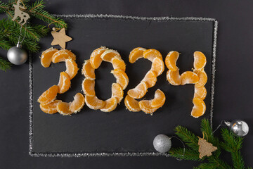 New Year 2024 is approaching. The figures are laid out with mandarin slices on a black background,...