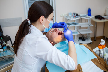 Doctor woman dentist treats the patient's teeth, proper dental care. Dental care and hygiene concept. Selective focus.