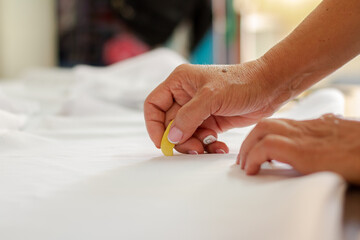 Female dressmaker's hands marking fabric for clothing design. Sewing work and clothing design.