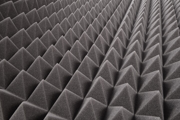 The pattern of the dark gray sound proof panel of polyurethane foam. Shockproof foam. Background of sound absorbing sponge. Selective focus.  - obrazy, fototapety, plakaty