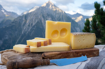 Cheese collection, French beaufort, abondance, emmental, tomme de savoie cheeses served outdoor in Savoy region, with Alpine mountains peaks on background