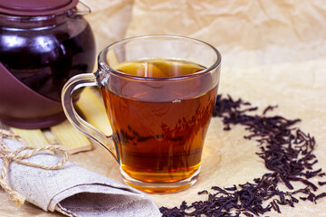 Fresh organic aromatic black tea in the glass cup on light background.