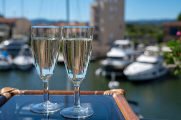 Summer party with sparkling champagne wine and sail boats haven of Port Grimaud on background, Provence, France