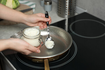 Woman cooking with coconut oil on induction stove, closeup