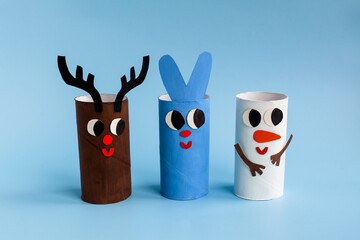 Holiday easy DIY craft idea for kids. Toilet paper roll tube toy rabbit, snowman, deer on blue background. Creative New Year and Christmas decoration eco-friendly, reuse, recycle handmade concept