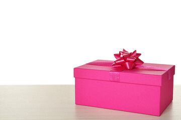 Pink gift box with bow on wooden table against white background, space for text