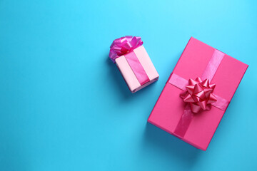Pink gift boxes on light blue background, flat lay. Space for text