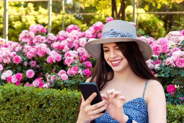 Young woman using the smart phone at park at spring summer season