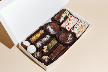 closeup various handmade vegan chocolate candies n the gift box on yellow background