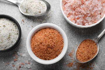 Different kinds of salt on grey table, flat lay
