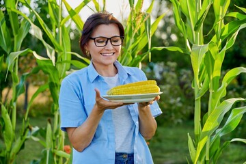 Middle-aged woman with boiled corn in plate