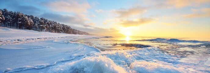 Panoramic view of the frozen Baltic sea shore at sunset. Ice fragments close-up, snow-covered...