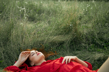 pretty woman in red dress lies on the grass freedom landscape