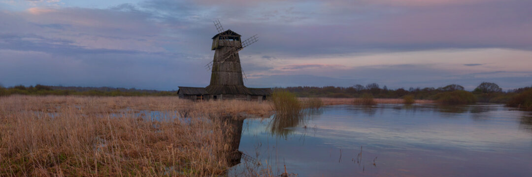 A ruined windmill on the bank of a river after the high water in spring